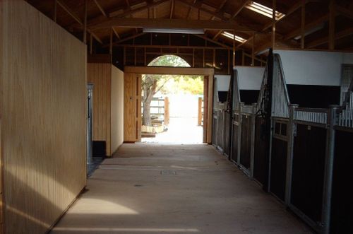An internal view of a Warwick Buildings American Barn designed using Victorian style stable fronts and controllable roof ventilation. A stall area is located between a tackroom to one side and a utility room to the other