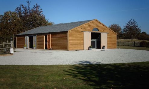 An external view of American Barn in Feather Edge Boarding featuring Ultra Profile Grey Felt Tiles. Several door positions and over stable adjustable roof ventilation, provides controllable air movement inside the building